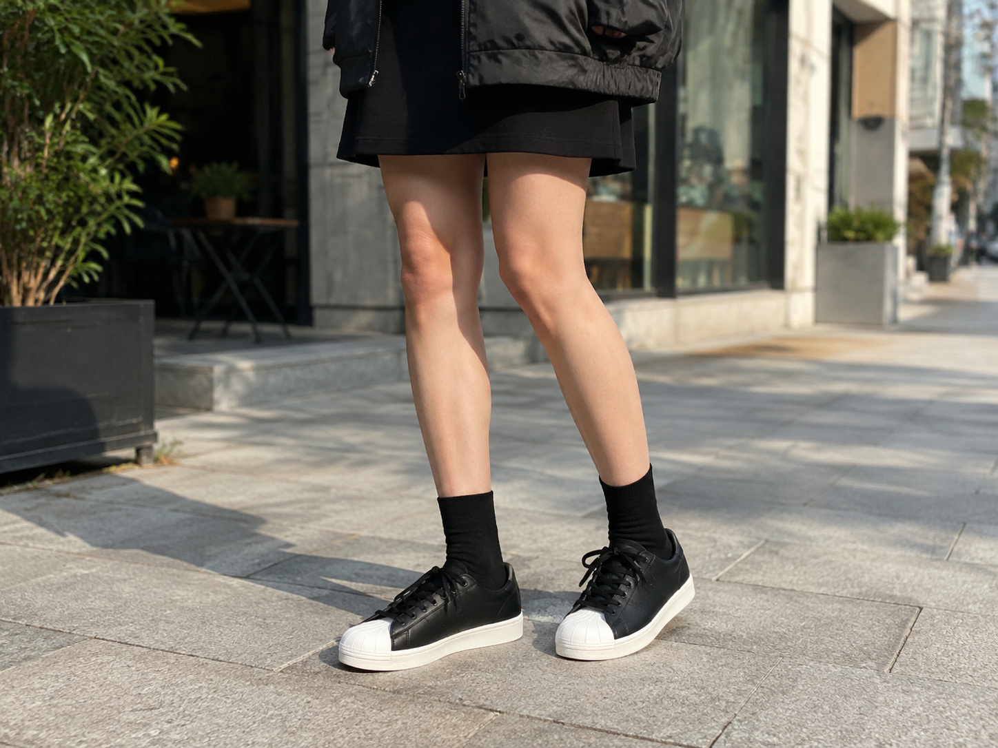 Jennie-style outfit featuring a black track top and skirt paired with white Shelltoe Superstar 2s as a focal point